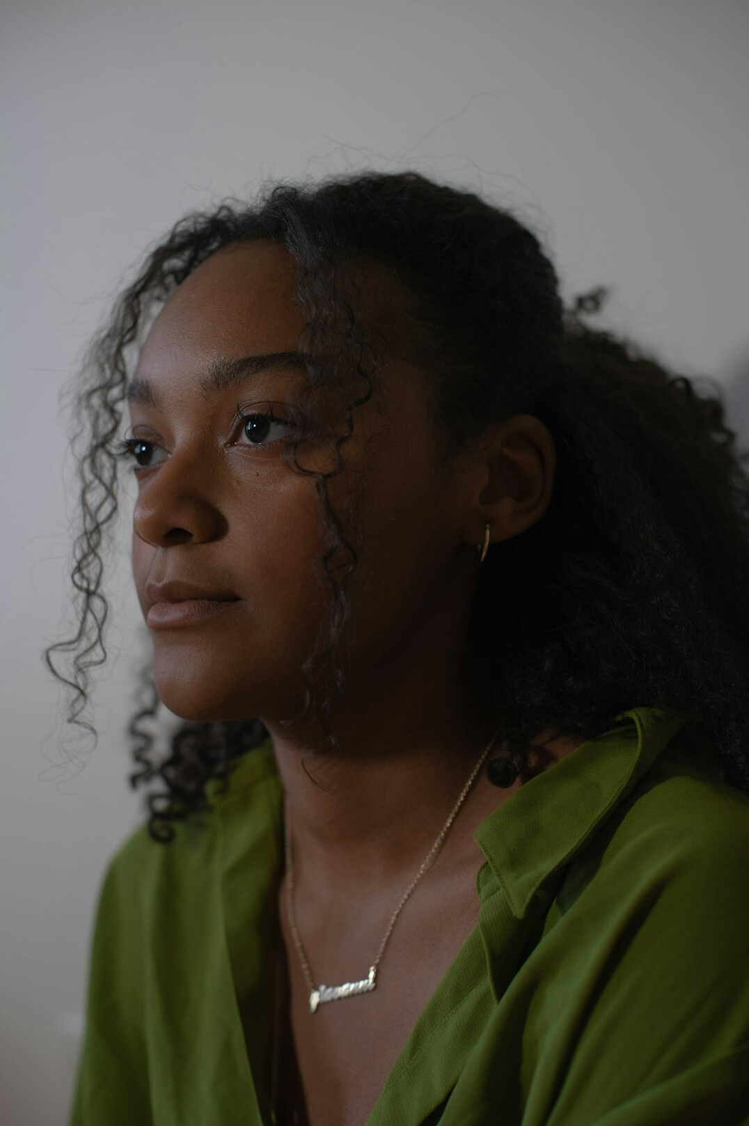 Portrait of a woman with curly hair and a warm smile in a green top