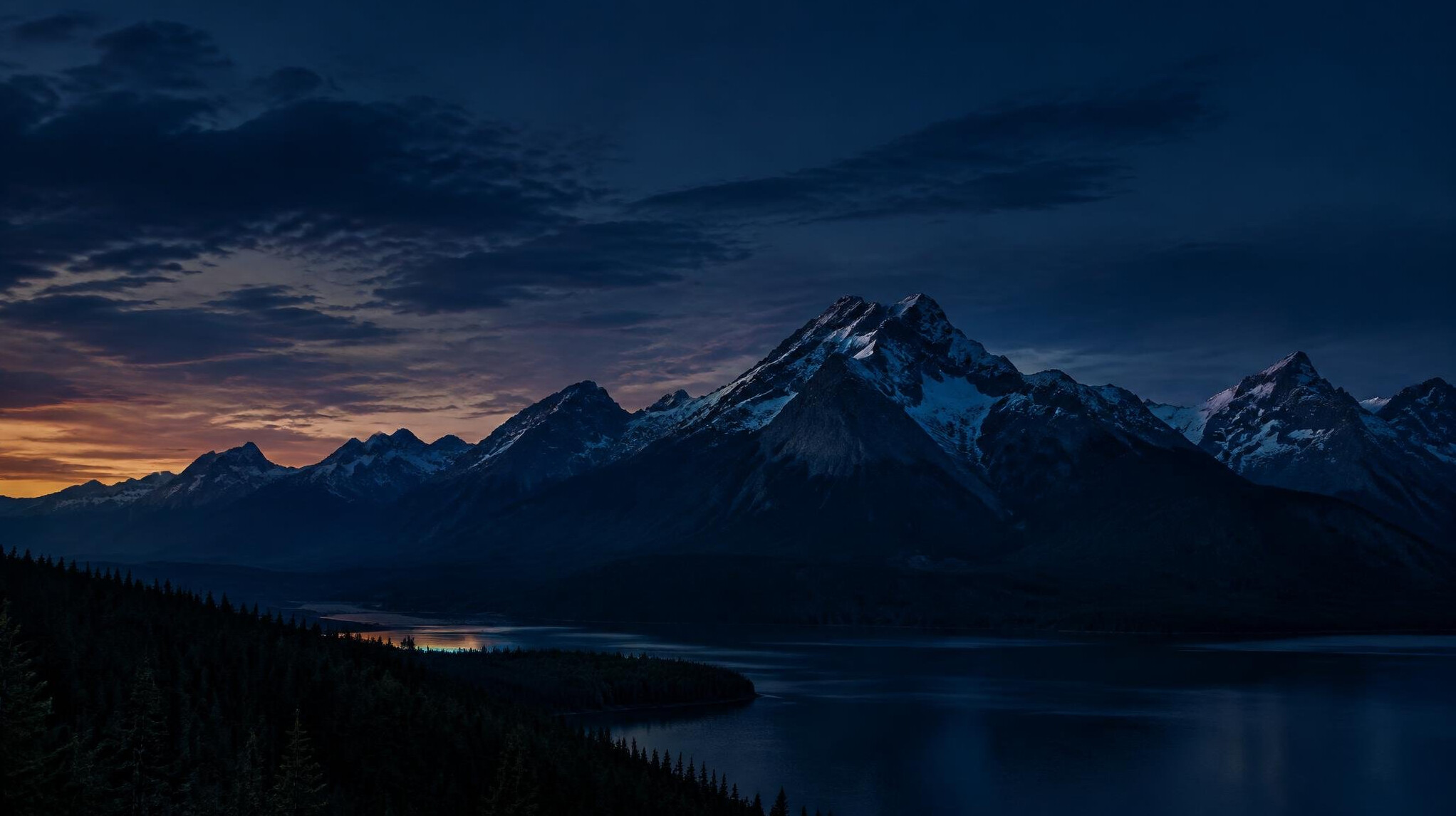 Dark mountain range at dusk with a deep blue sky
